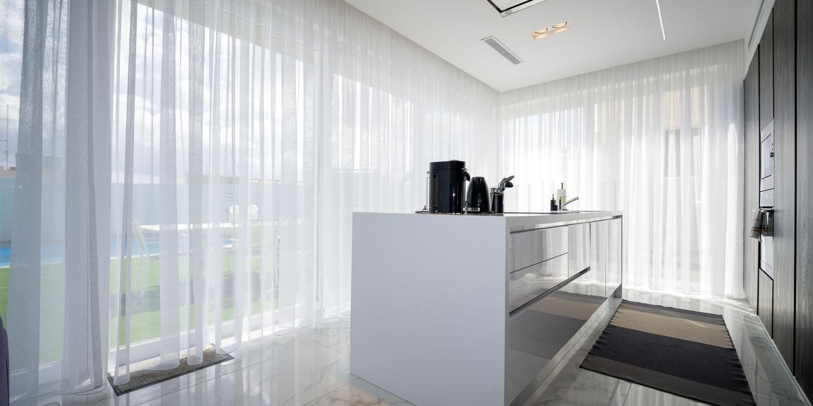 An airy room wrapped in floor-to-ceiling white sheer voile curtains