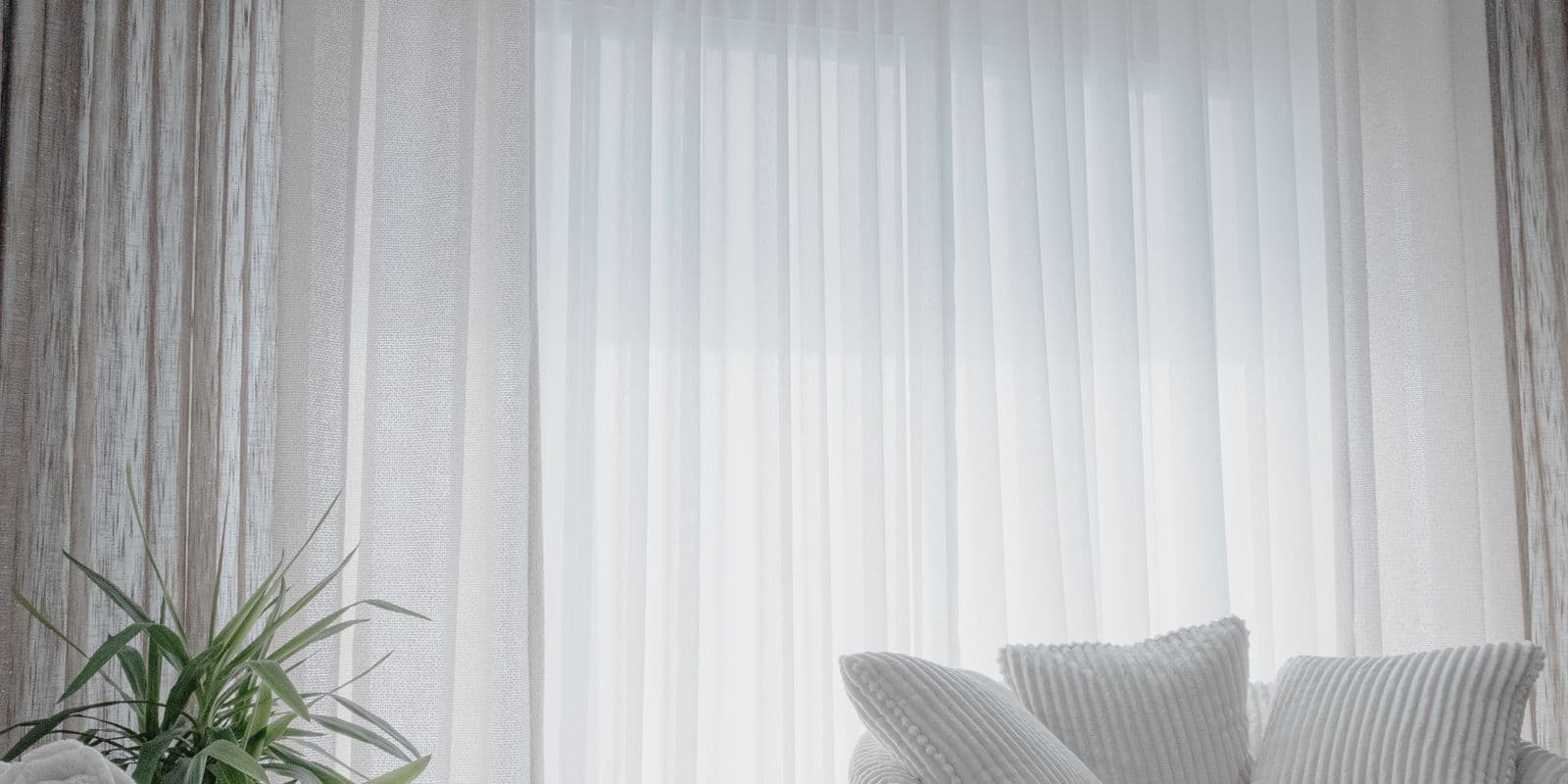 A serene room with tall white sheers and soft layered drapery