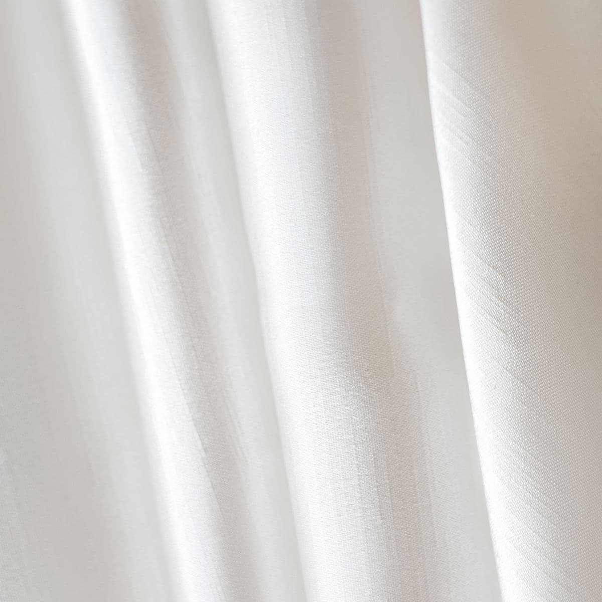 Close-up of pale ivory satin drapery fabric in soft folds