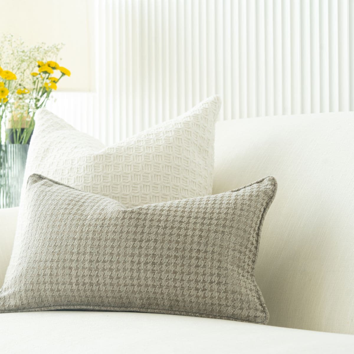 Cream and soft-grey textured cushions on a white sofa