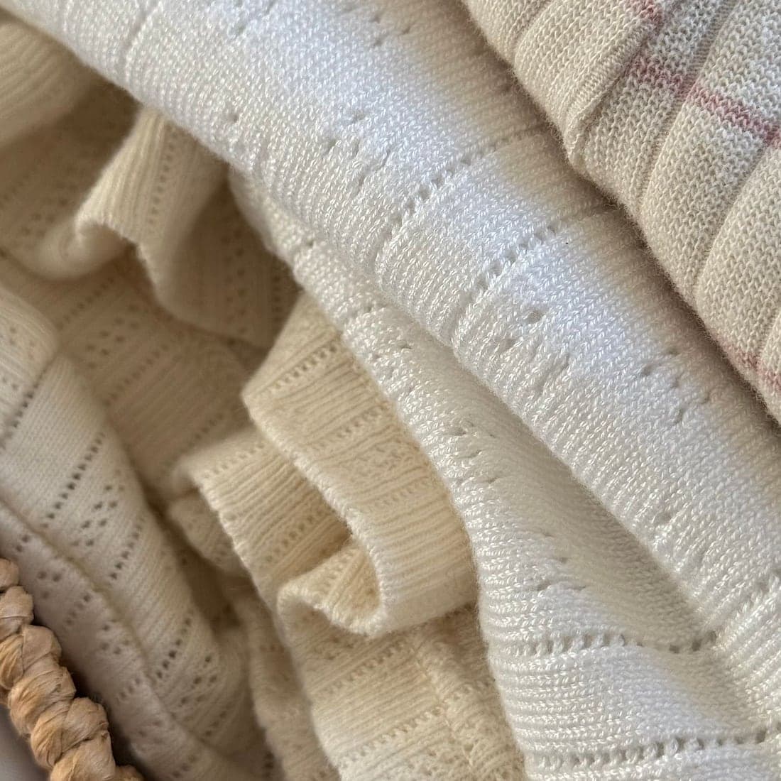 A stack of folded cream pointelle-knit throws