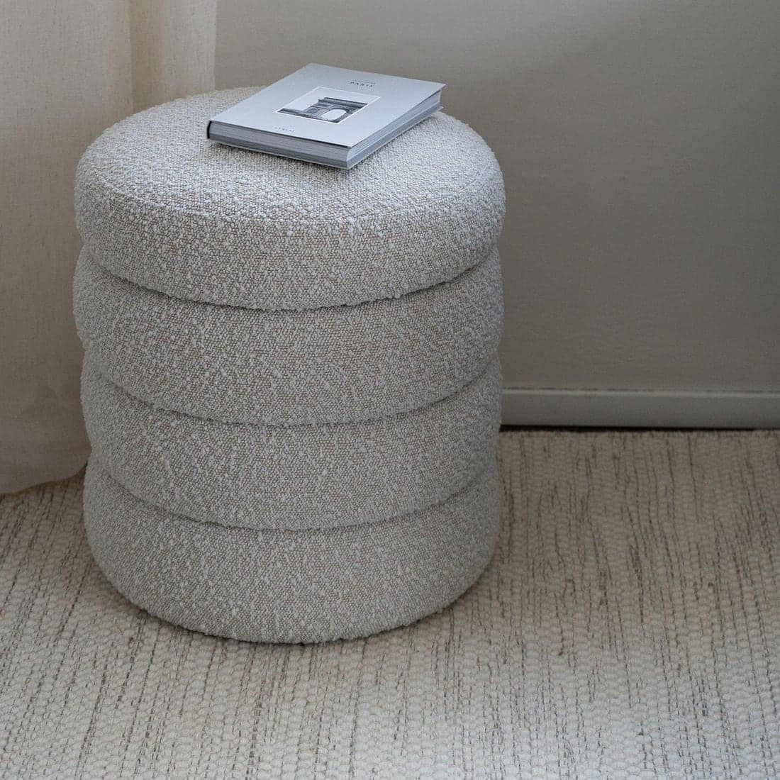 A cream bouclé accent pouf in soft daylight