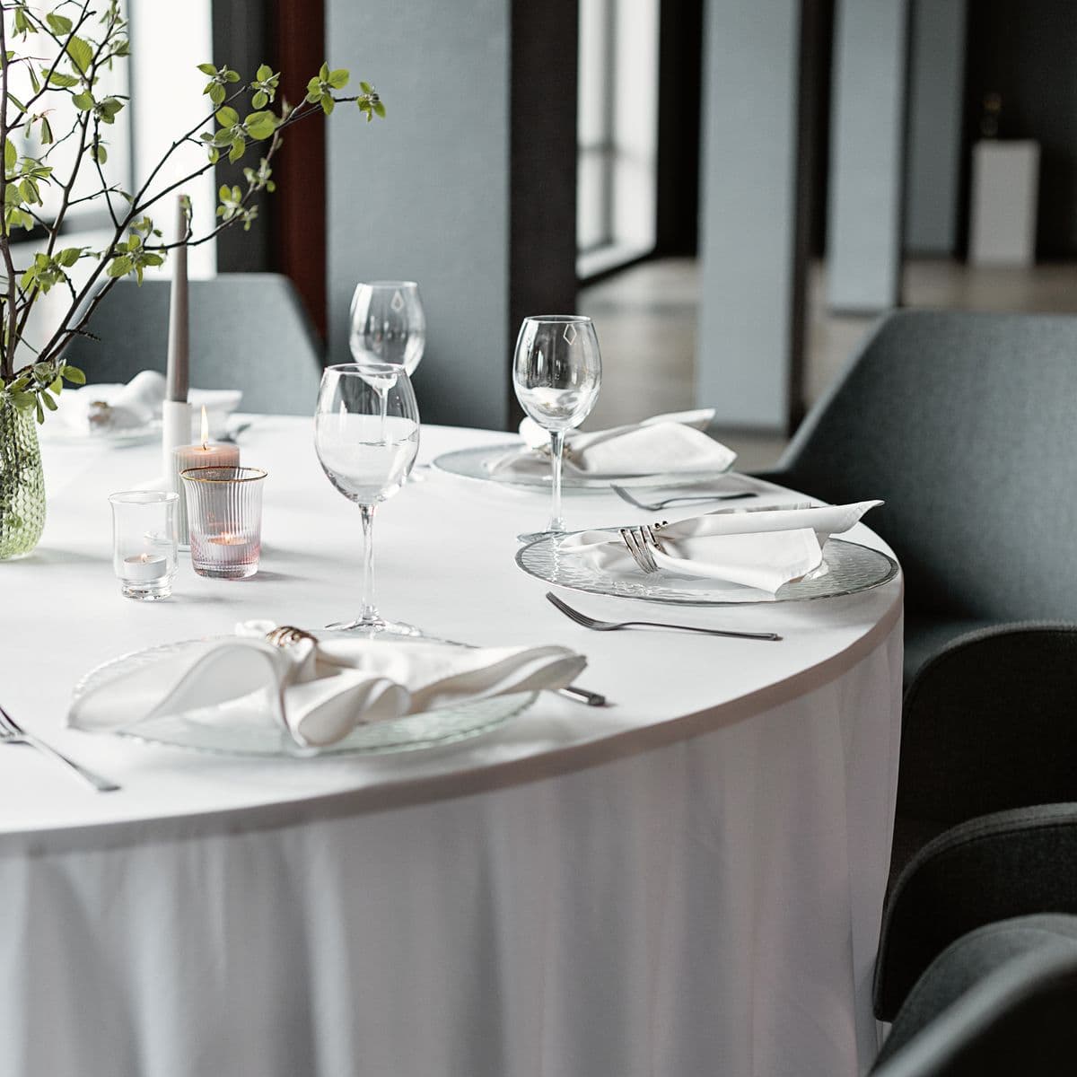 A bright white round banquet table with neat place settings