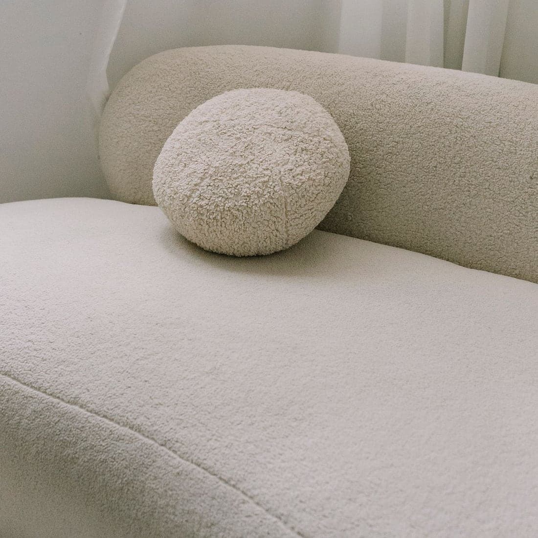 A soft cream textured cushion in an airy setting