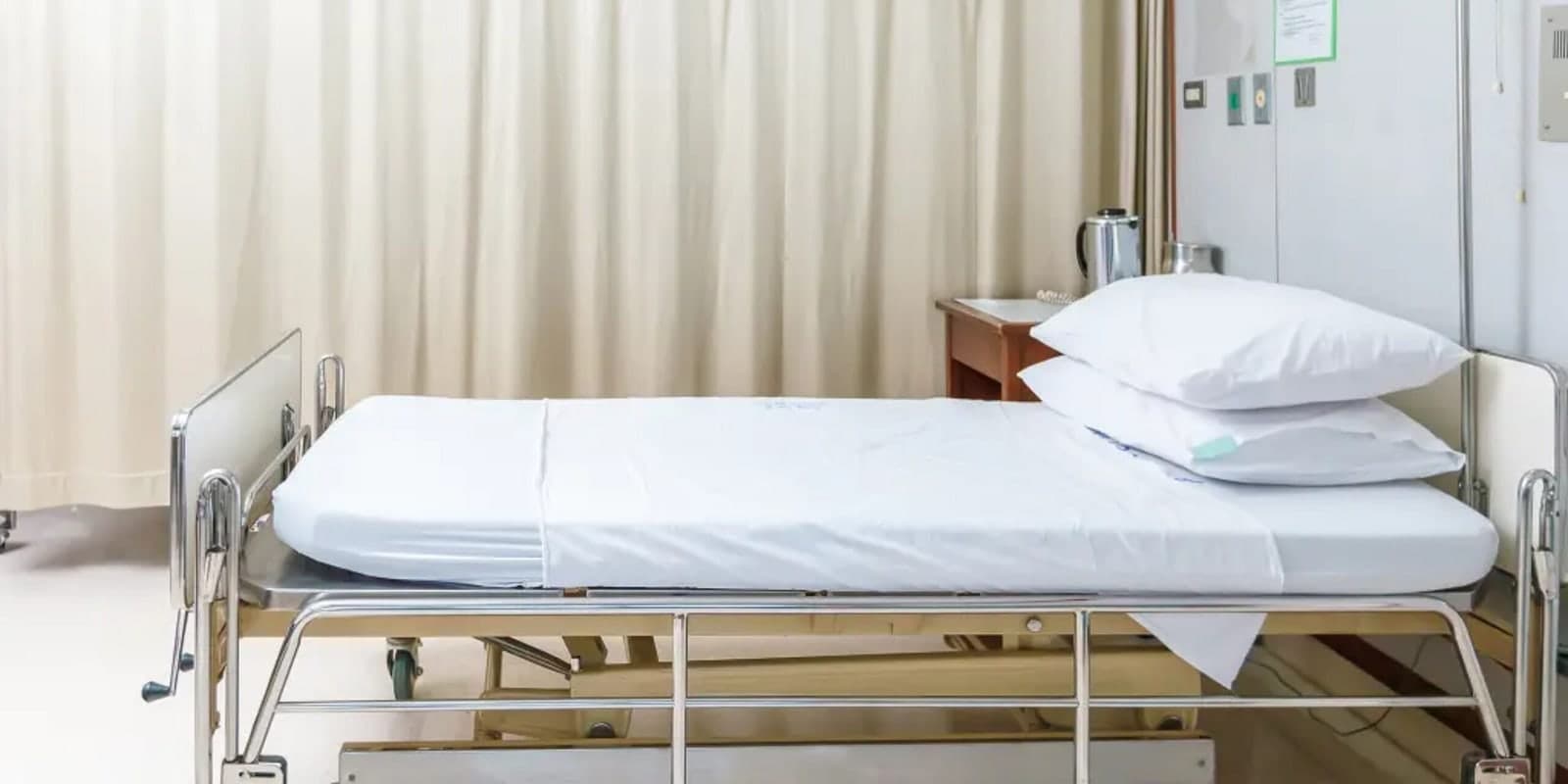 A hospital bed made up with crisp white linen