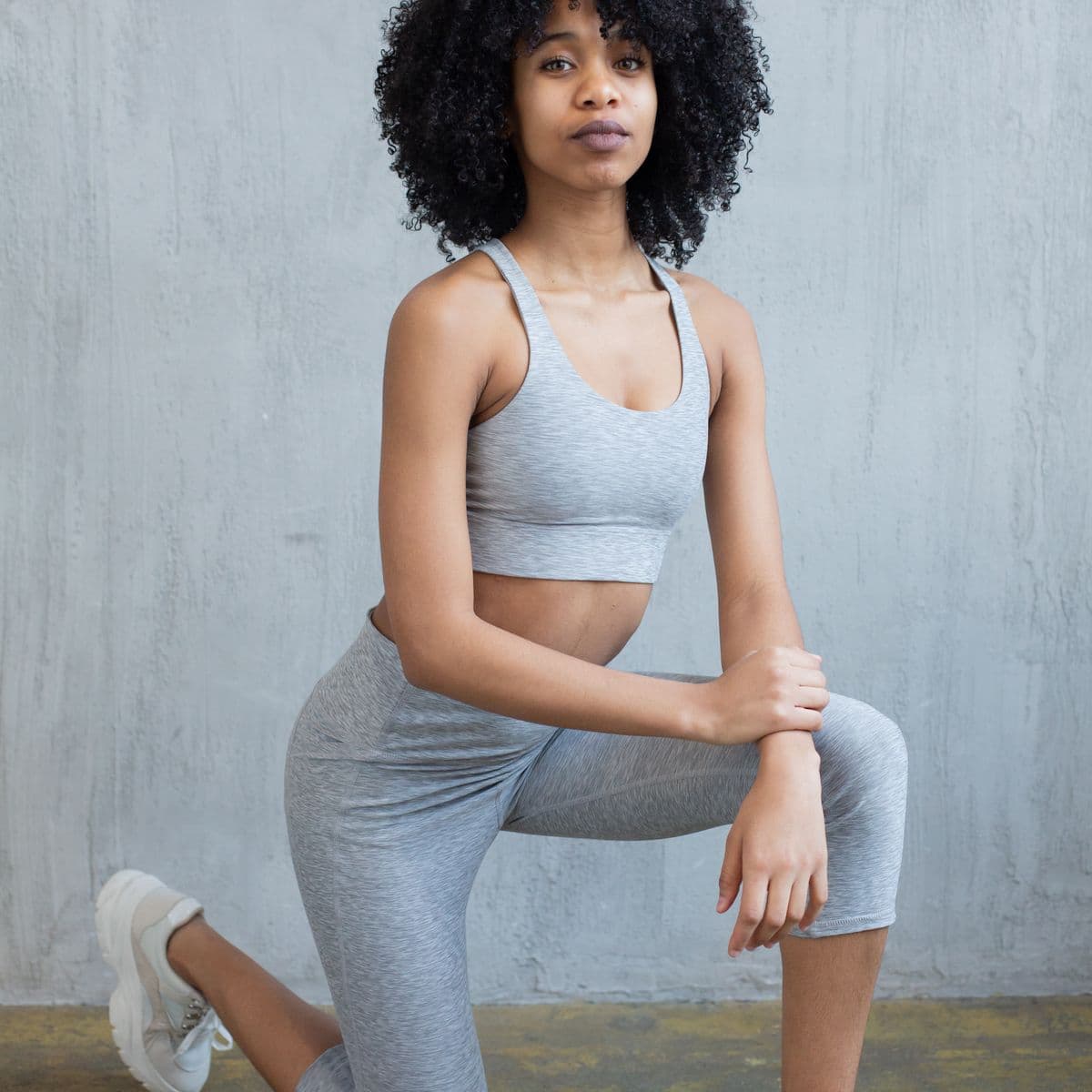 Athletic model in a heather-grey set in a lunge