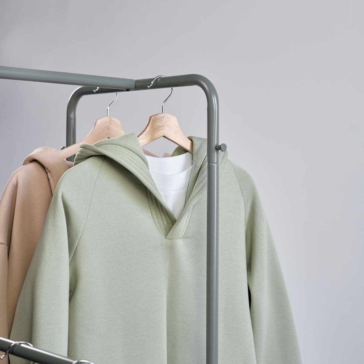 A sage hooded sport pullover on a rail