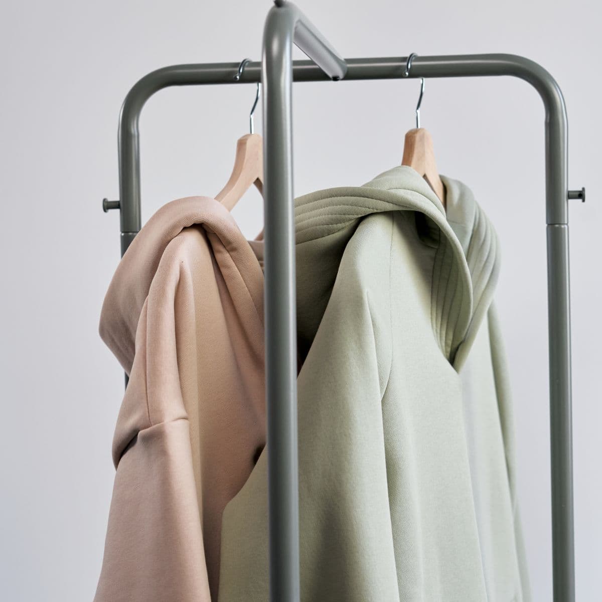 Stone and sage hoodies on wooden hangers