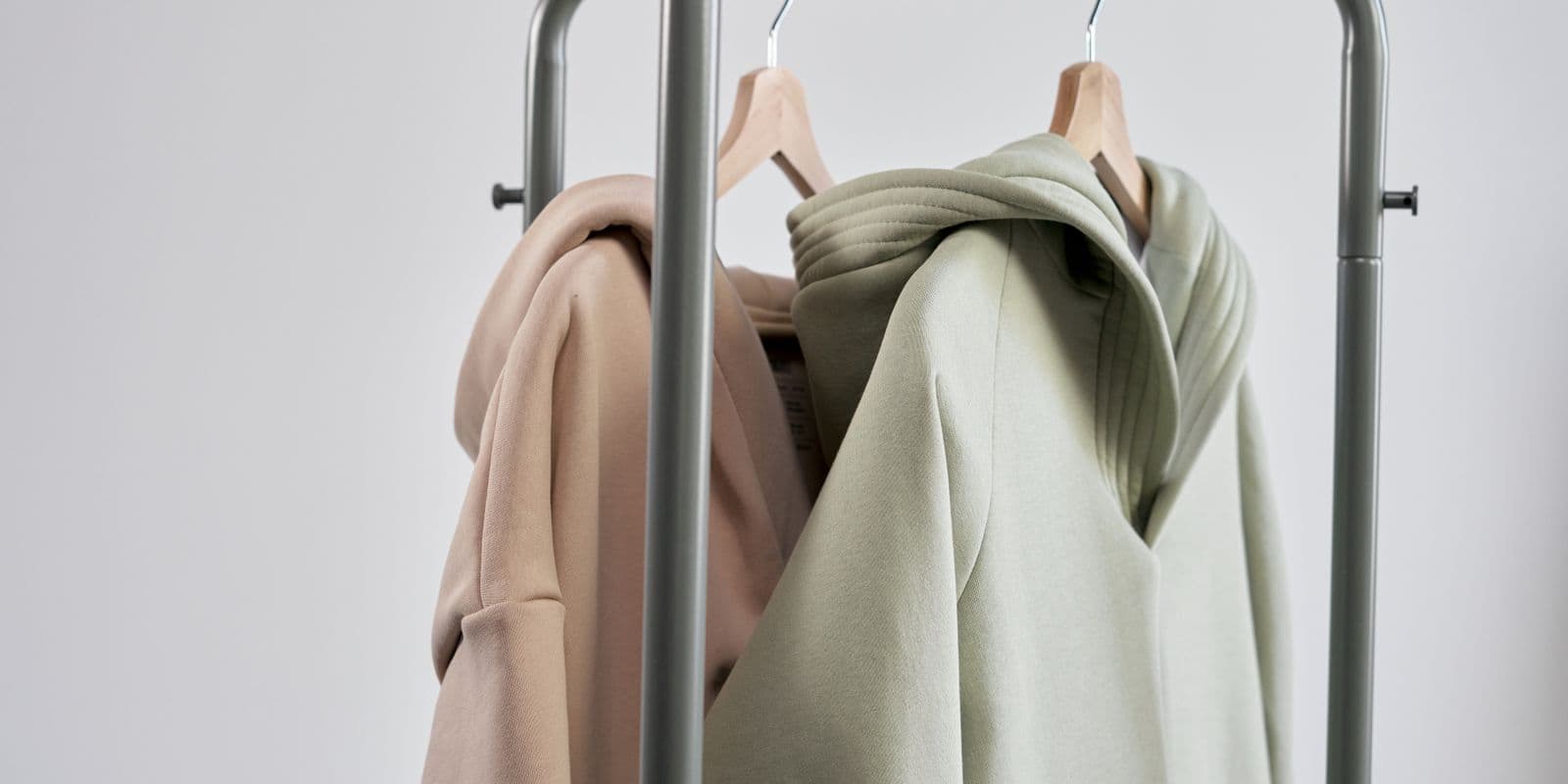 Sage and stone hooded pullovers on a minimalist rail
