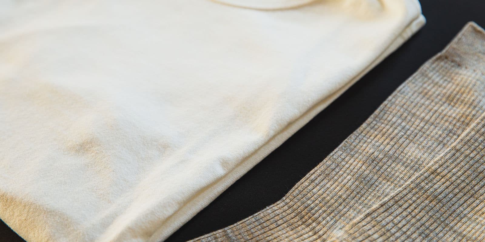 A folded cream tee beside ribbed performance fabric