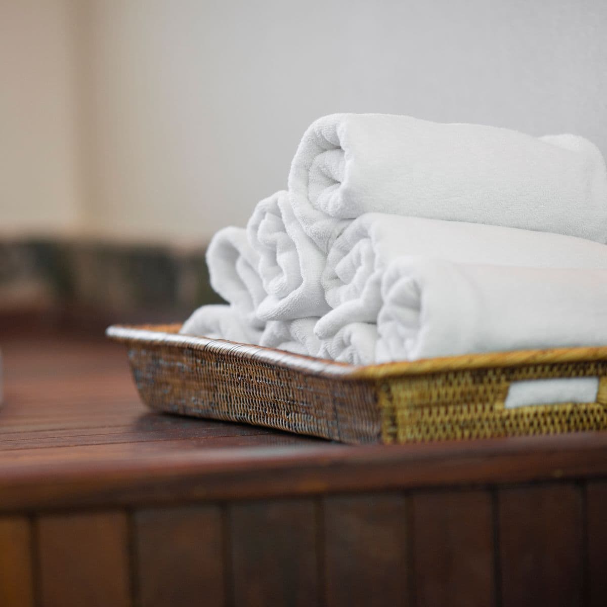 Rolled white gym towels in a woven tray