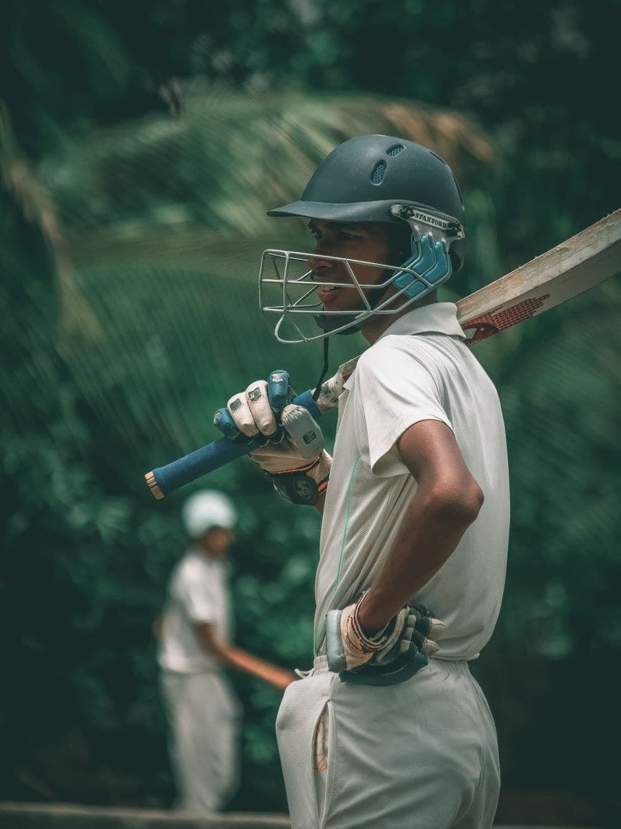 A cricketer in whites holding a bat