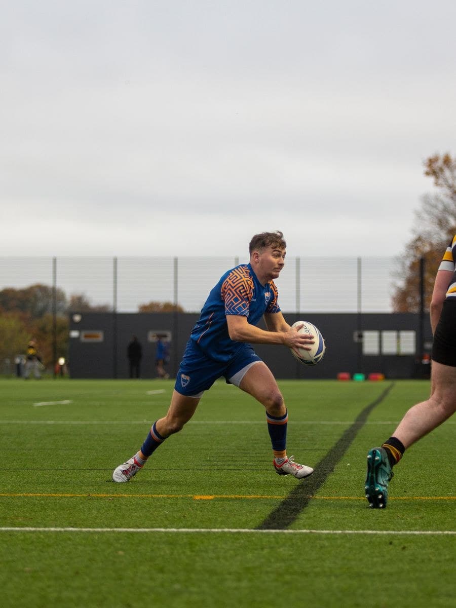 A rugby player in sublimated kit passing the ball