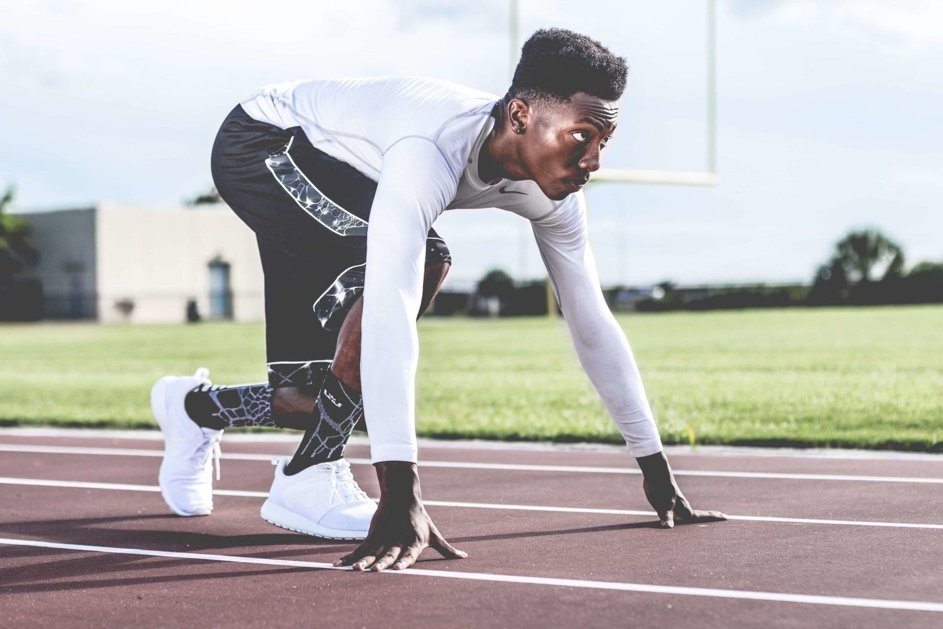 An athlete in a compression base layer at the start of a sprint