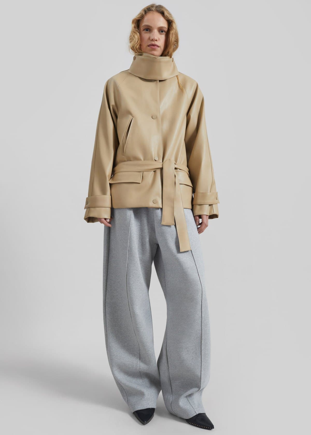 Model in a beige belted funnel-neck leather jacket