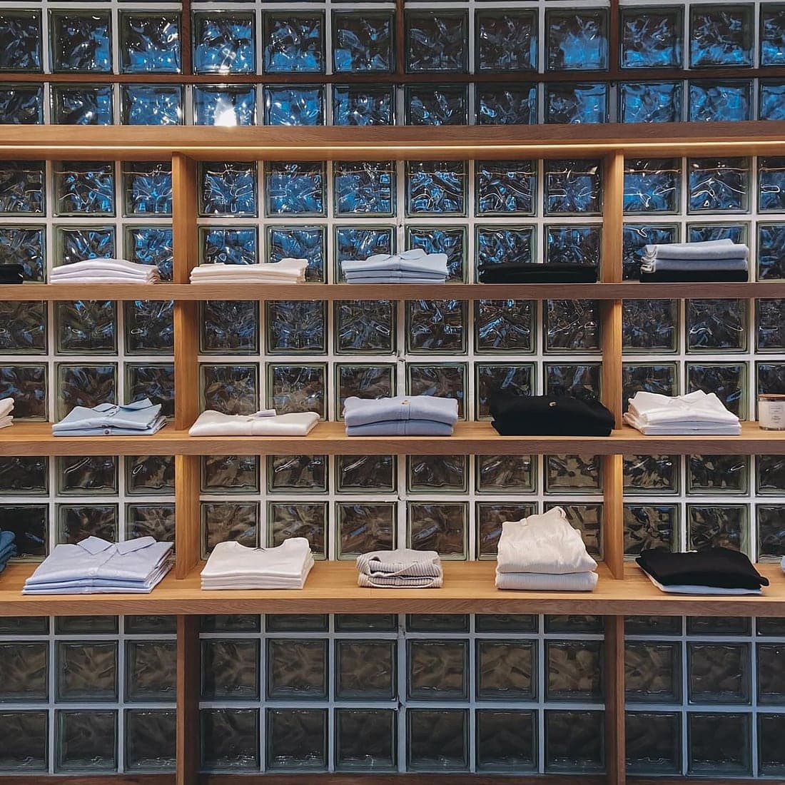 Folded white and light blue shirts on clean wooden shelves