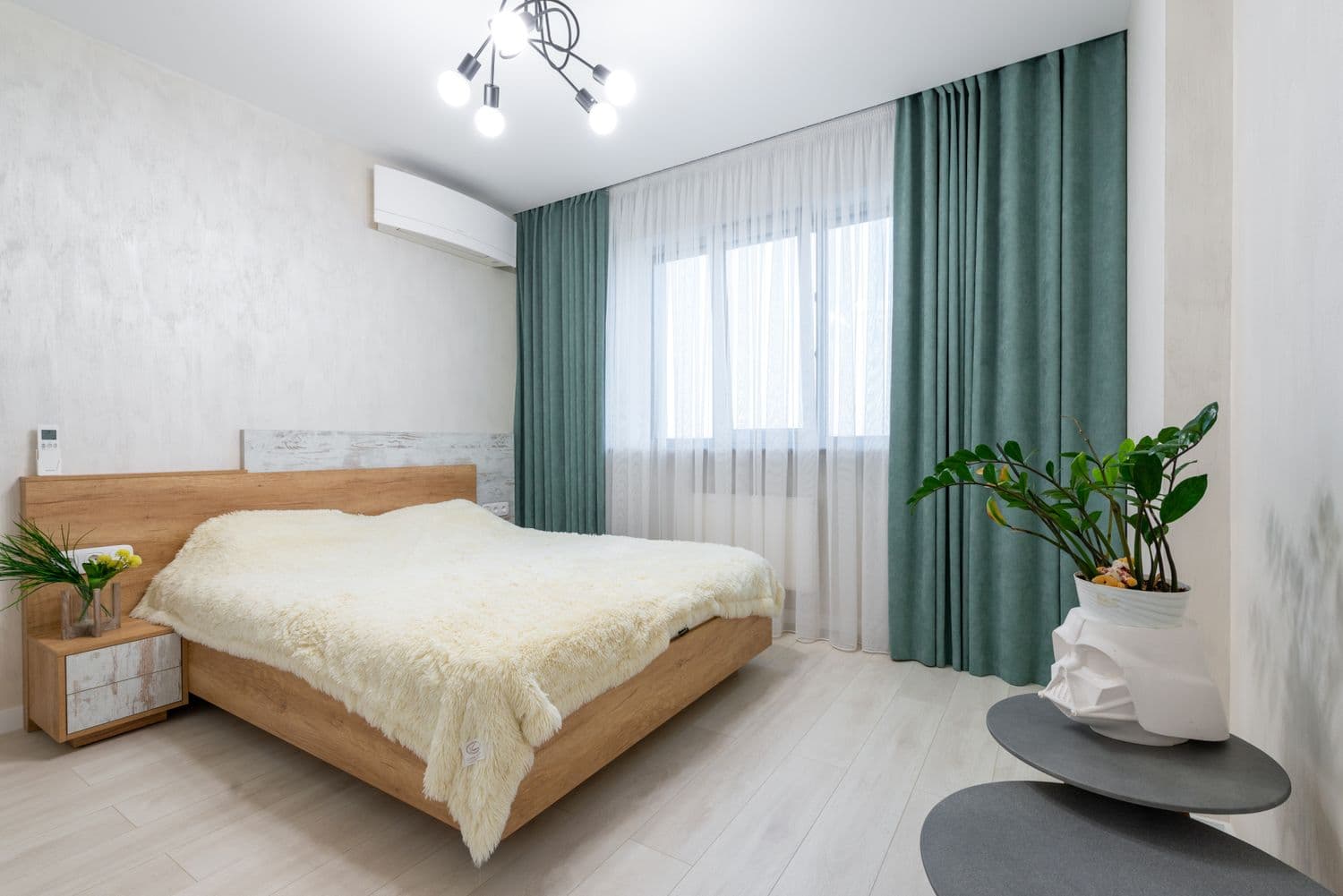 Layered white sheer and sage drapery in a bright bedroom