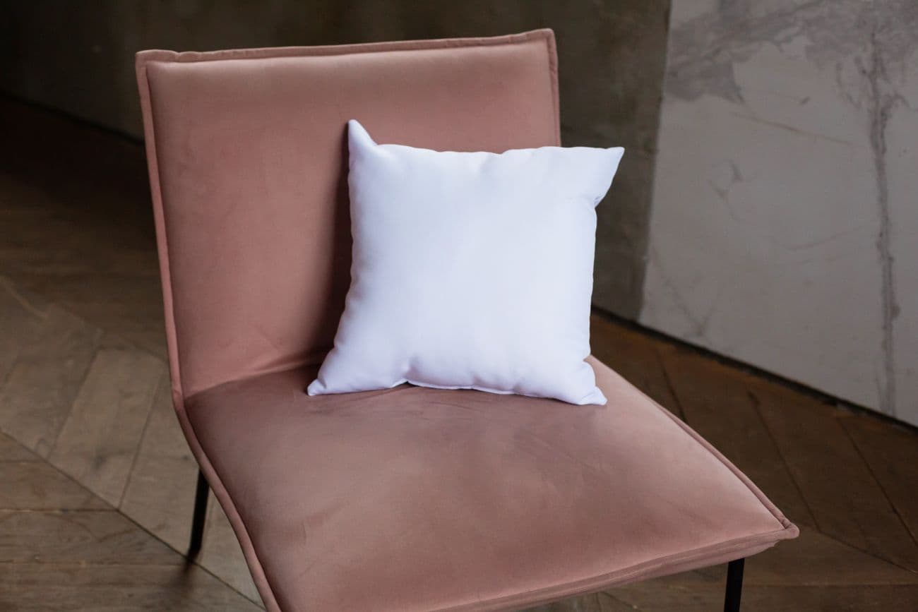 White scatter pillow on a soft blush velvet chair