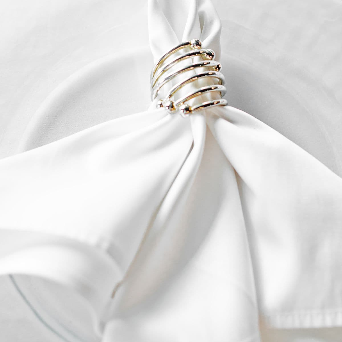 A pure white linen napkin cinched in a silver napkin ring