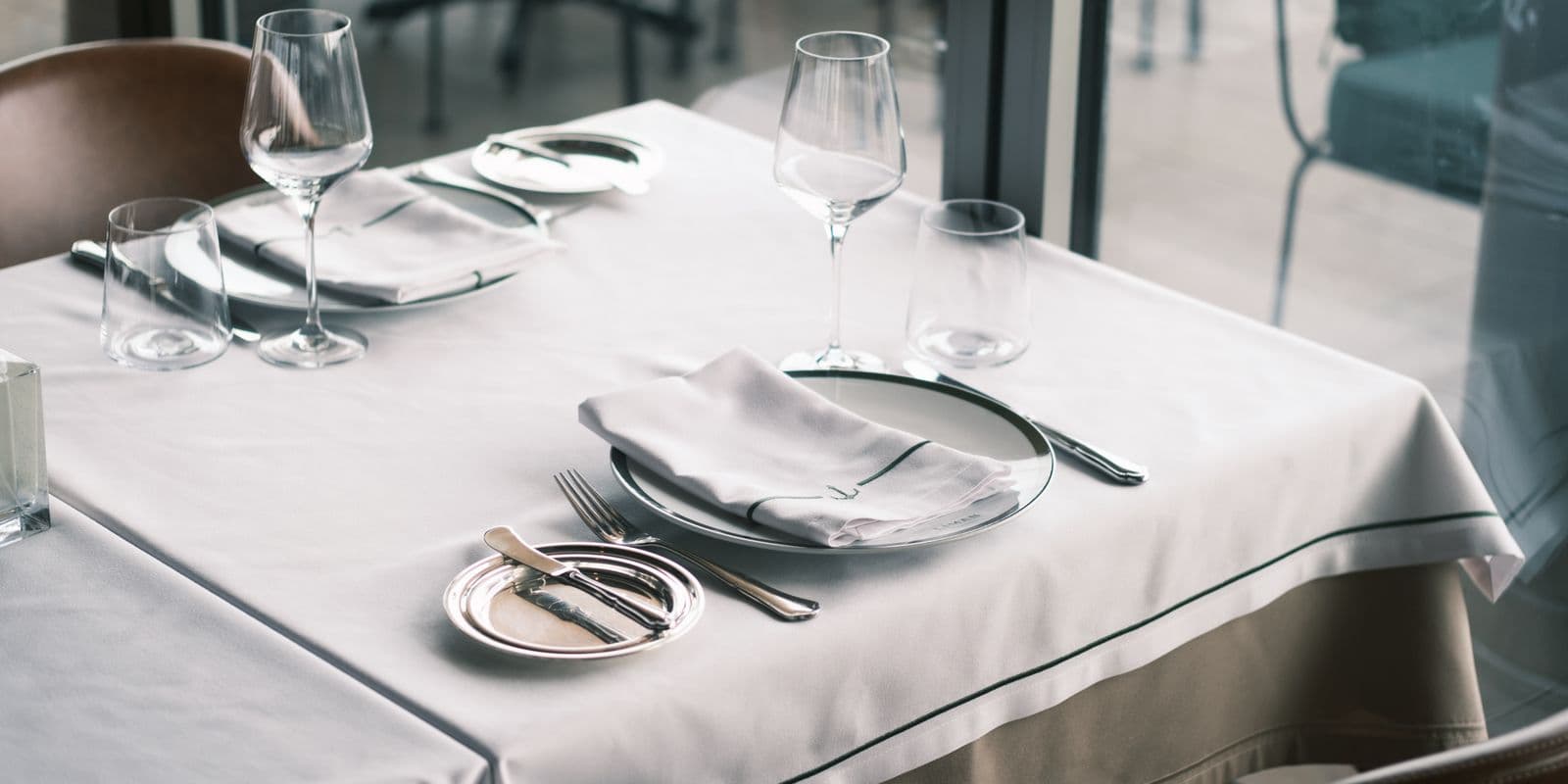 A white-linen restaurant table set with a folded napkin and crystal glasses