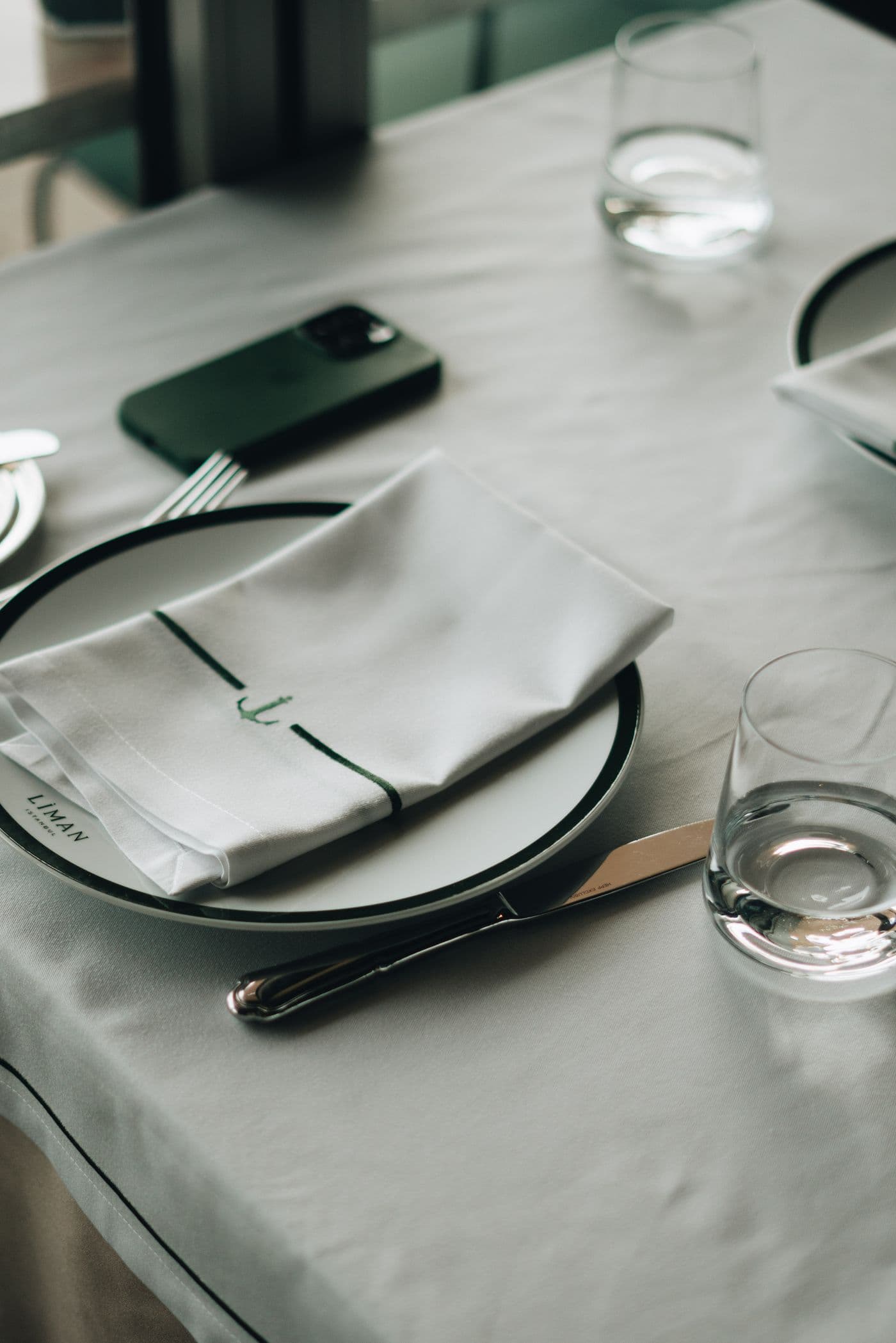 A restaurant table laid with white plates and napkins